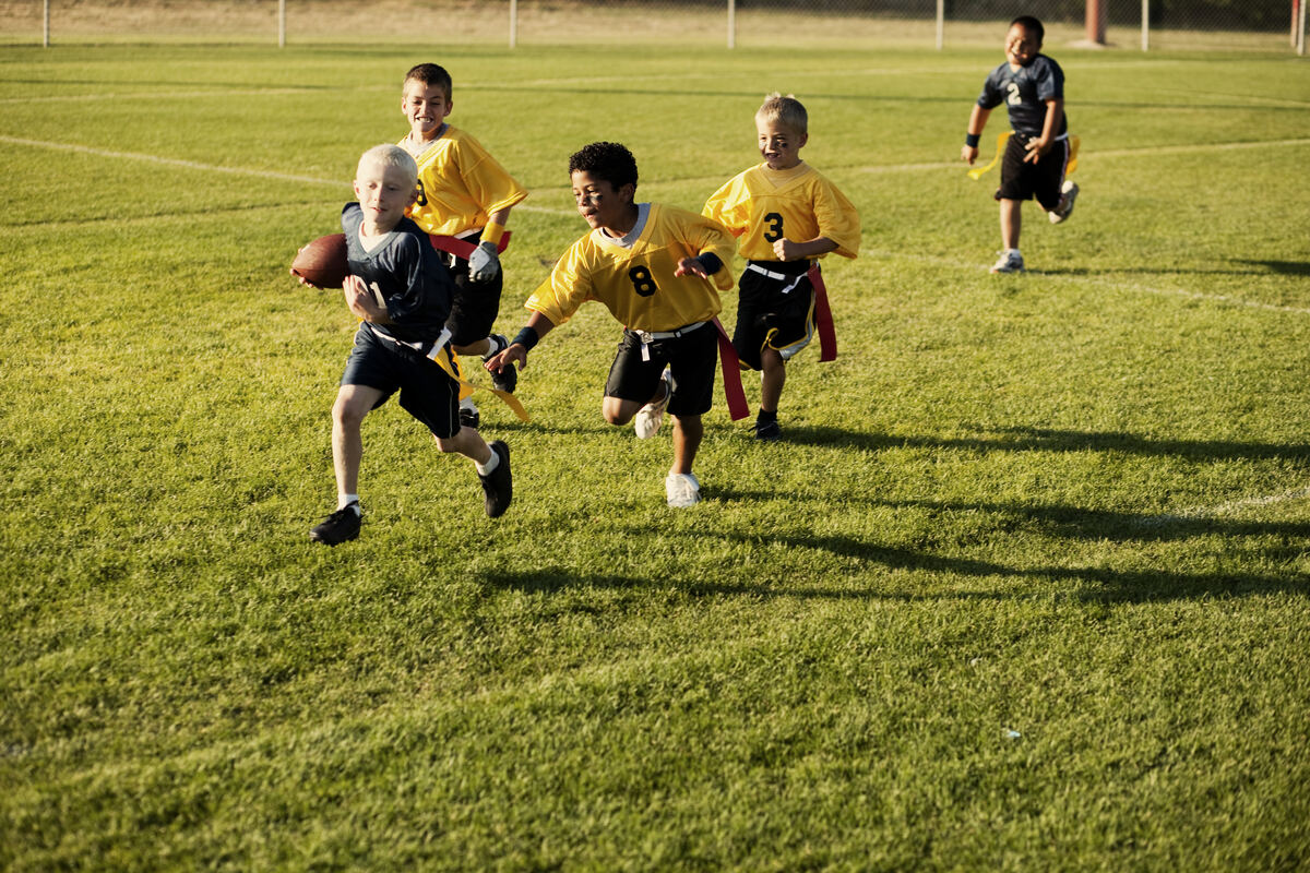 Youth flag football players running with the ball